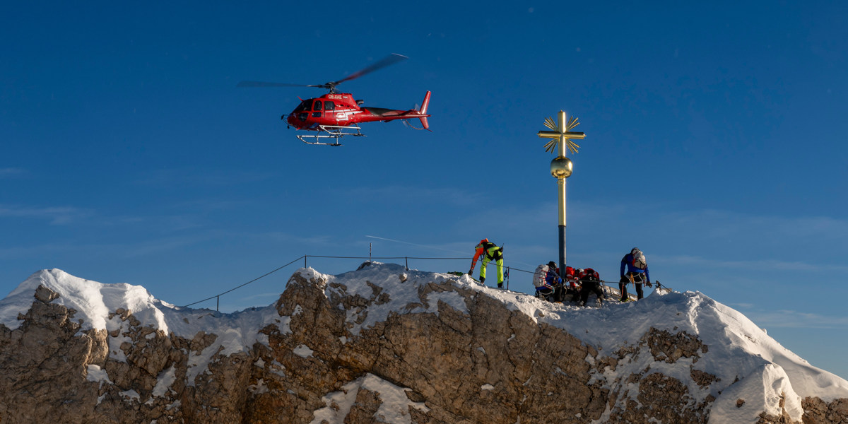 Das renovierte Gipfelkreuz steht nach seinem Transport per Helikopter wieder auf der Zugspitze und wird in seiner Vorrichtung montiert. Zuvor wurde es von Aufklebern befreit, restauriert und neu vergoldet.