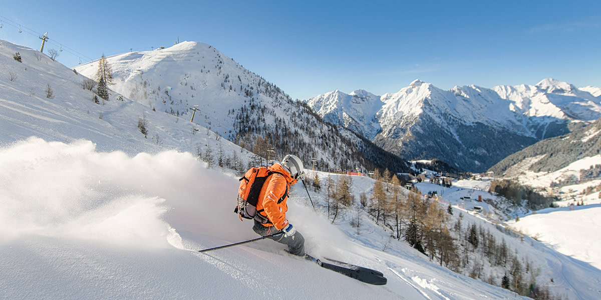 Skifahren in Zeiten des Klimawandels: Beschneite Pisten, grüne Hänge.
