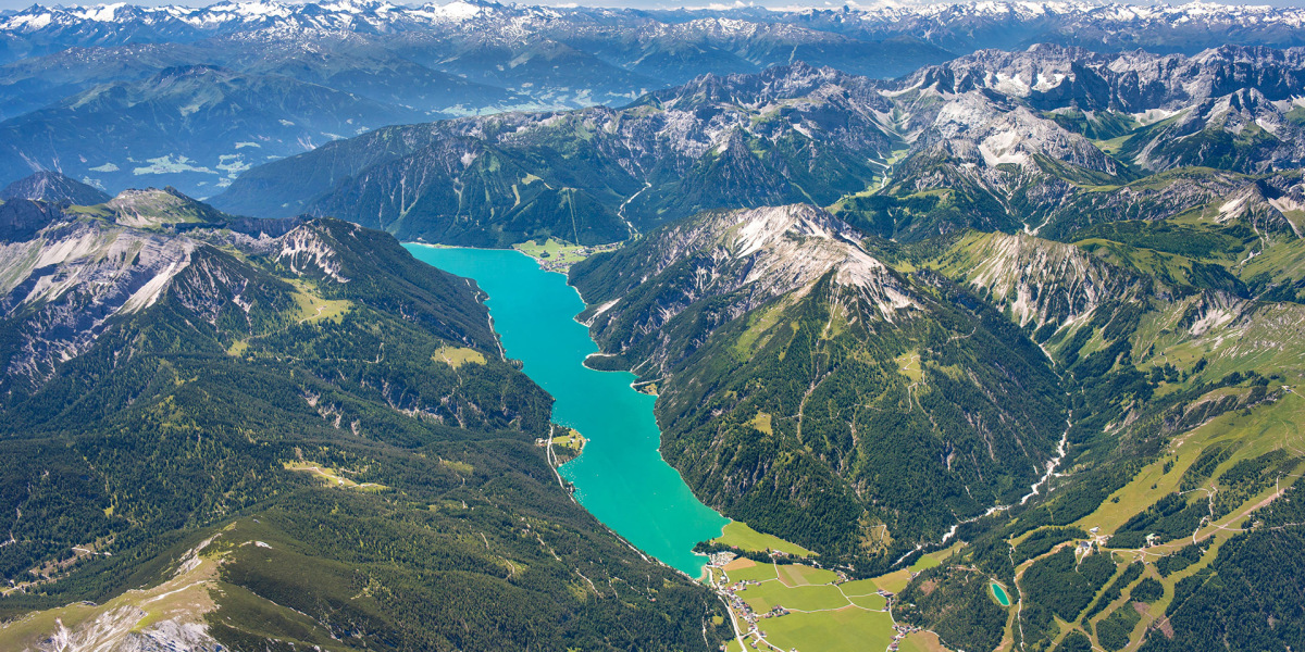 Sommerlicher Höhenflug: der Achensee mit Rofan (l.), Karwendel und dem Alpenhauptkamm in der Ferne.