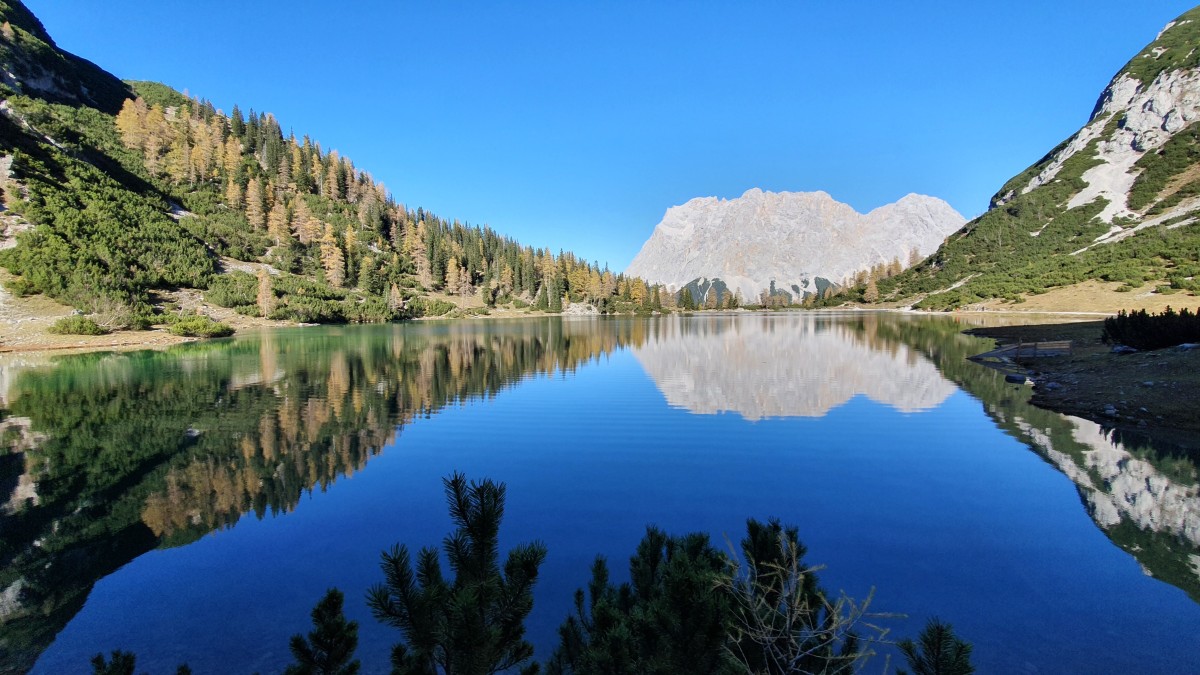 Perfekte Spiegelung des Zugspitzmassivs im Seebensee in der goldenen Stunde