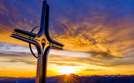 Das Gipfelkreuz des Hohen Göll leuchtet in der Abendsonne.