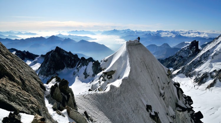 Wie eine gefrorene Woge schlägt die fotogenste Wechte am Kuffnergrat über den Felsen zusammen. Im Hintergrund das Aostatal, unten rechts die Aiguille Noire de Peuterey.