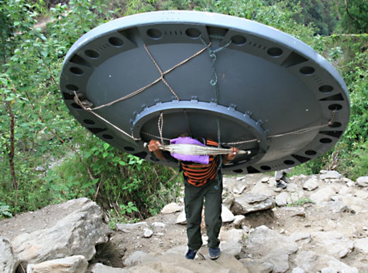 <p>Schwerstarbeit III: Ein Träger "balanciert" eine 80 Kilogramm schwere Satellitenschüssel durch unwegsames Gelände.</p>