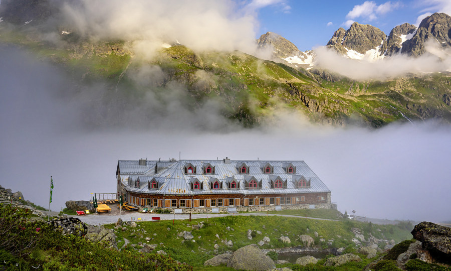 <p>Die Jamtalhütte taucht auf aus dem Morgennebel, darüber glänzen die Getschner Spitzen im frühen Sonnenlicht.</p>